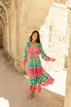 Afbeelding in Gallery-weergave laden, Boho Maxikleid von Piti Cuiti erhältlich bei Beach Addict. Entdecke das farbenfrohe Boho Maxikleid von Piti Cuiti, jetzt exklusiv im Online Shop Beach Addict. Das lange Kleid besticht durch seinen lebendigen Print aus Türkis, Pink und Orangetönen sowie seinen fließenden, leichten Stoff perfekt für Sommer, Urlaub und Strandtage. Mit seinem femininen V-Ausschnitt, den langen, transparenten Ärmeln und dem luftigen, mehrstufigen Rock vereint dieses Maxikleid Komfort und mediterranen Boho-Chic.